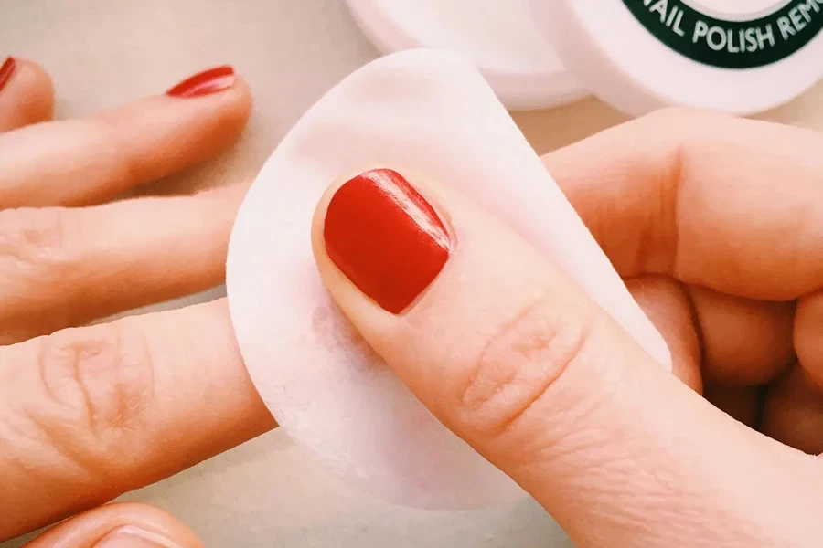 Personne utilisant un tampon démaquillant sur du vernis à ongles