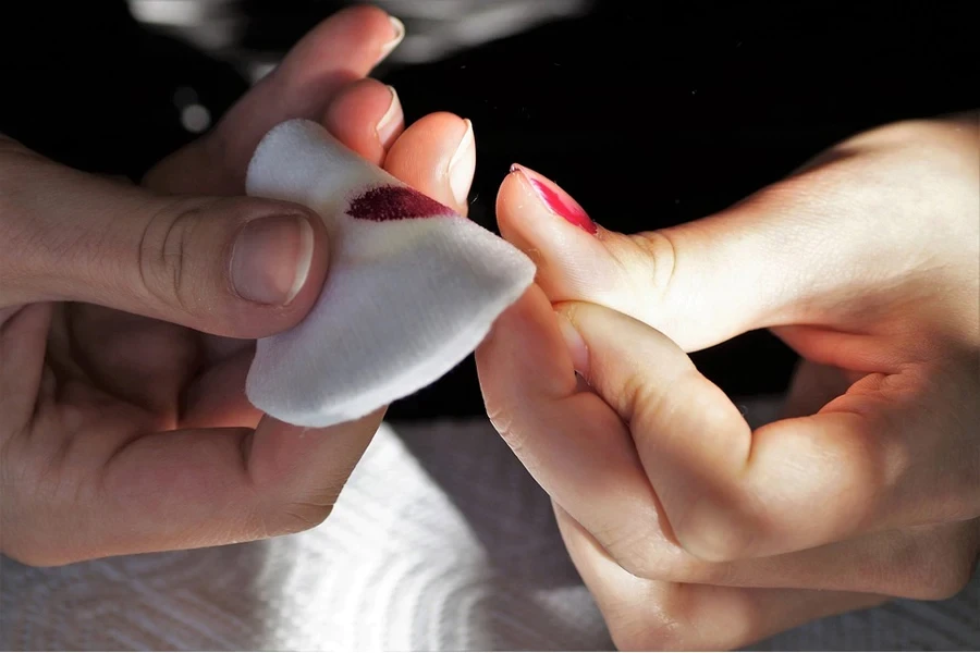 Person using a white polish remover pad