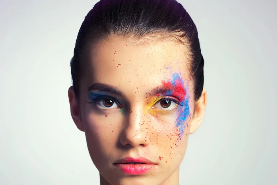 Person with expressive makeup over one eye and faux freckles