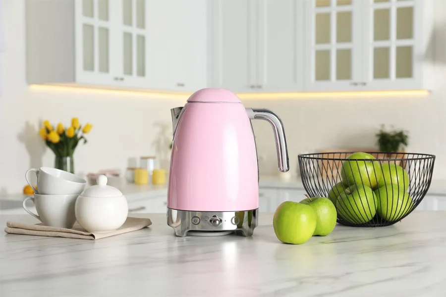 Pink electric kettle with tea set and apples in kitchen