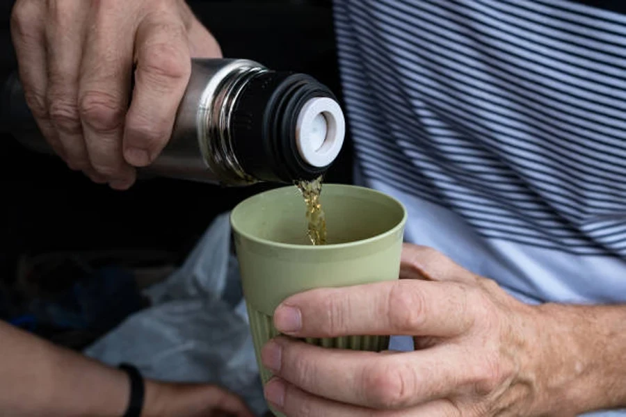 Grüner Campingbecher aus Kunststoff, in den Flüssigkeit gegossen wird