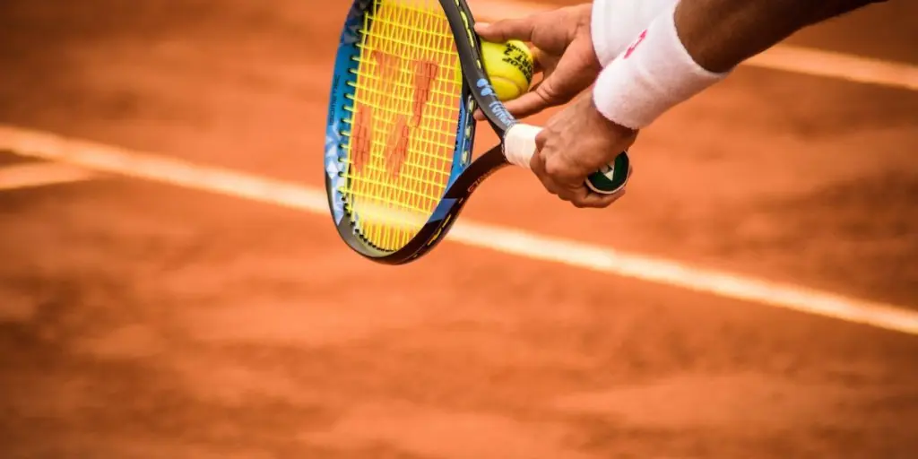 Jugador preparándose para sacar con una raqueta de tenis