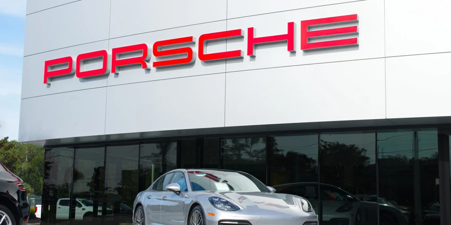 Porsche dealership with red logo on front of building and blue sky background