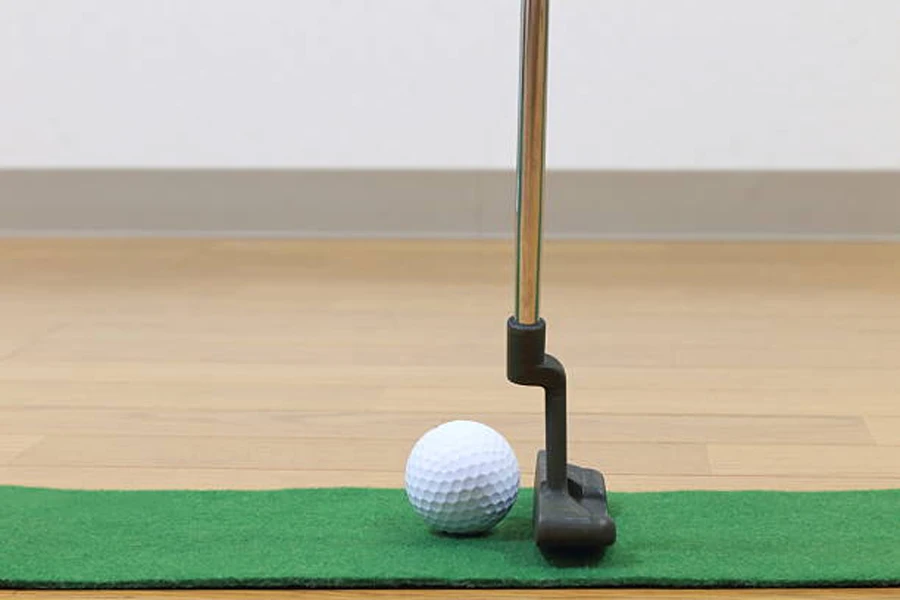 Putter lined up on artificial turf to hit golf ball