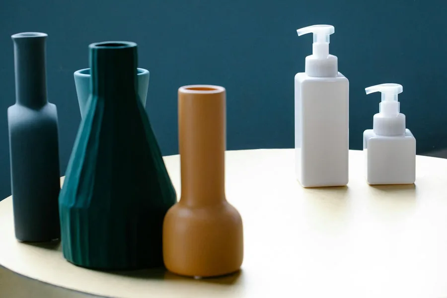 Set of bottles of lotions placed on table near various decorative vases