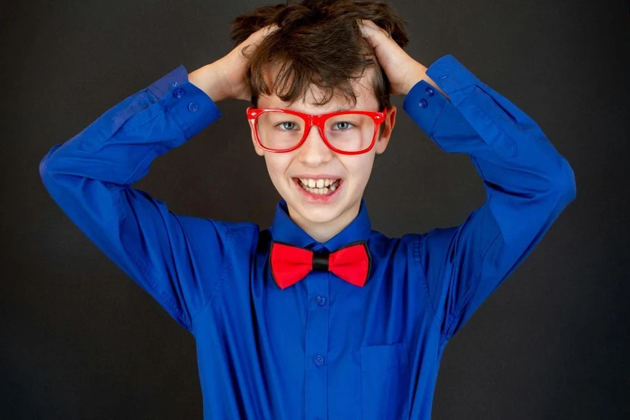 Smiling boy in colorful outfit clutching head