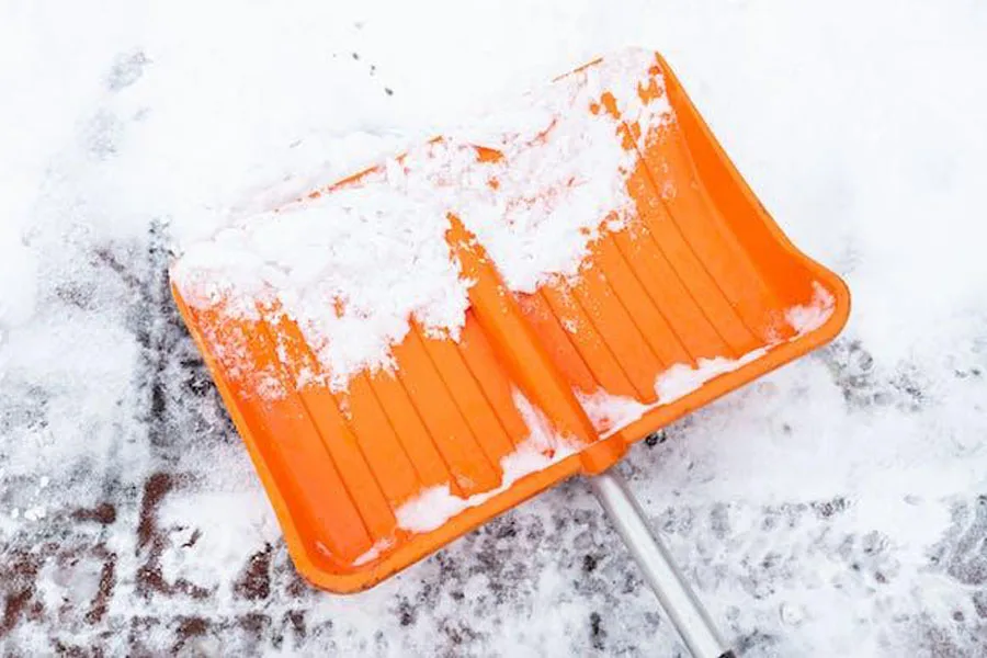 Snow on an orange shovel