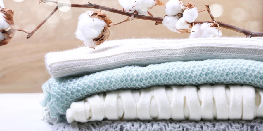Impilare i vestiti lavorati a maglia con fiori di cotone