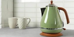 Stylish green electric kettle with tea cups
