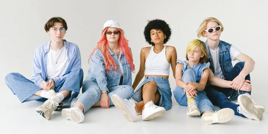 Stilvolle, gemischtrassige Models in Denim-Outfits sitzen auf dem Boden