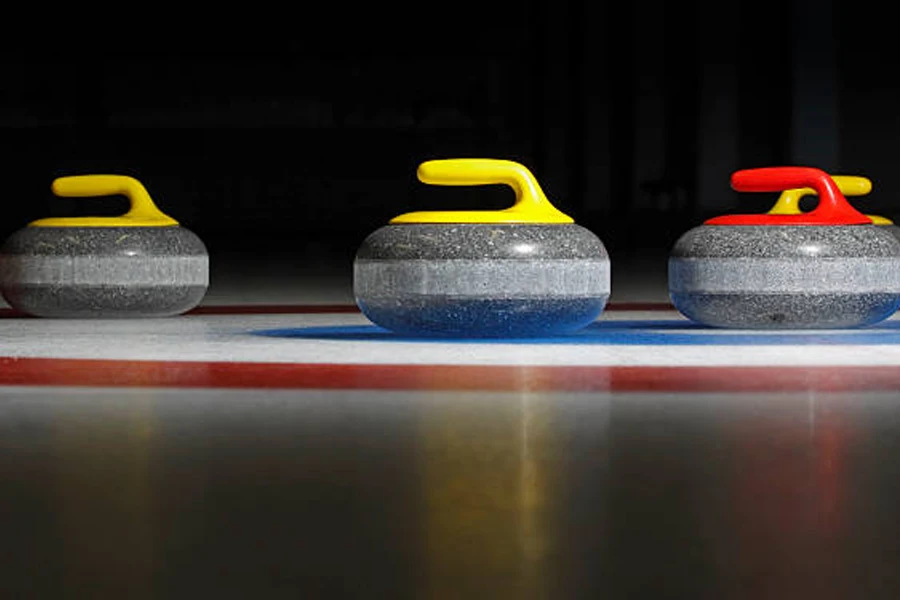 Three curling stones lined up on ice rink
