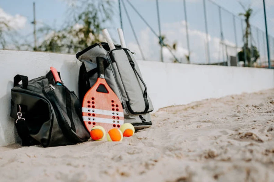 Zwei Strandtennisschlägertaschen und drei Bälle an der Wand