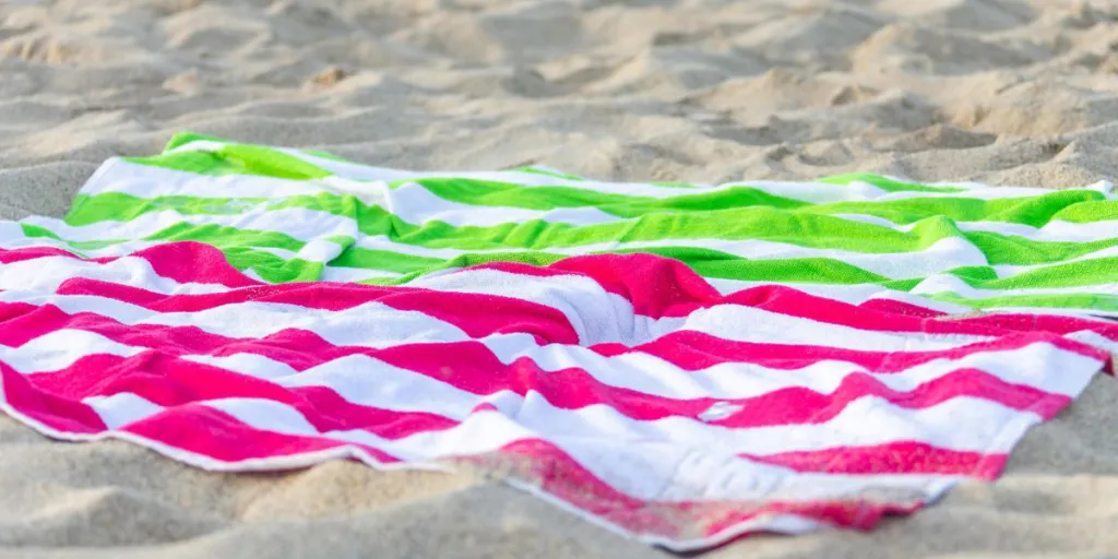 Two beach towels laying on sand
