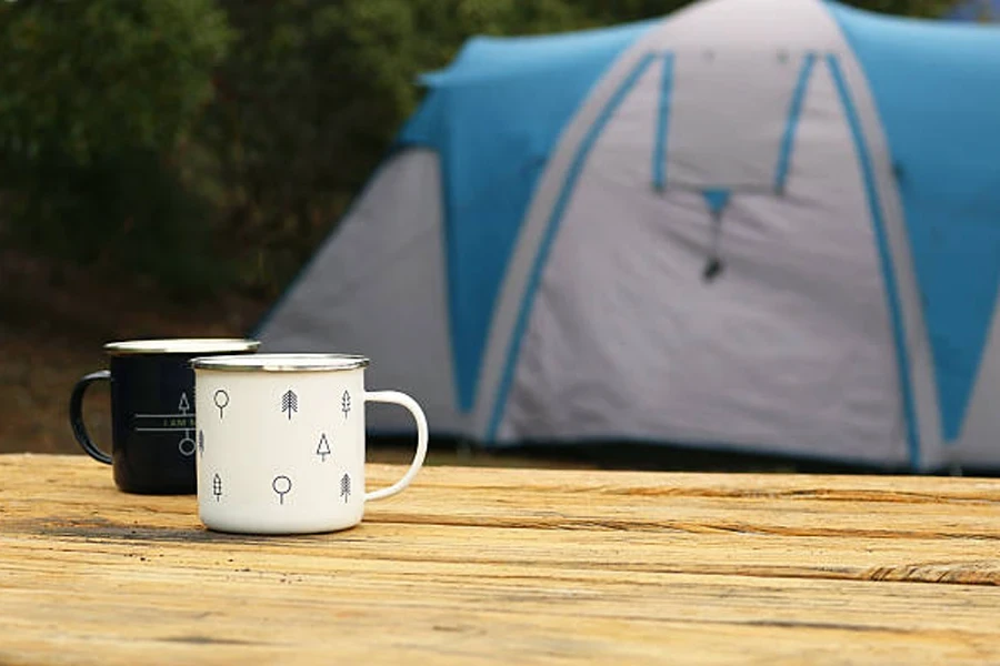 Zwei Campingbecher nebeneinander auf einem Holztisch