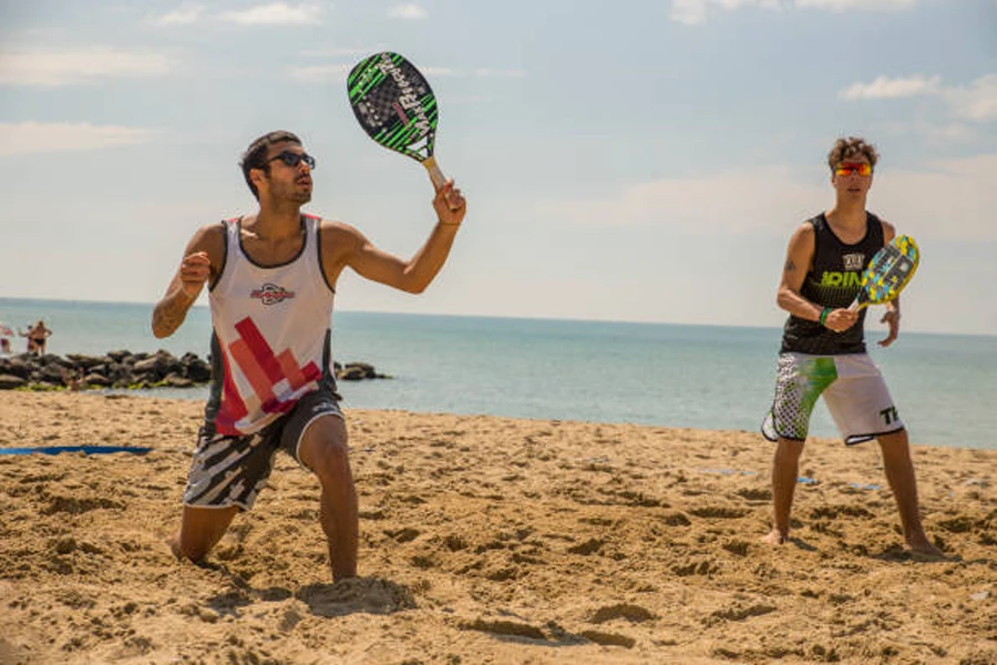 Two men playing beach tennis doubles next to sea