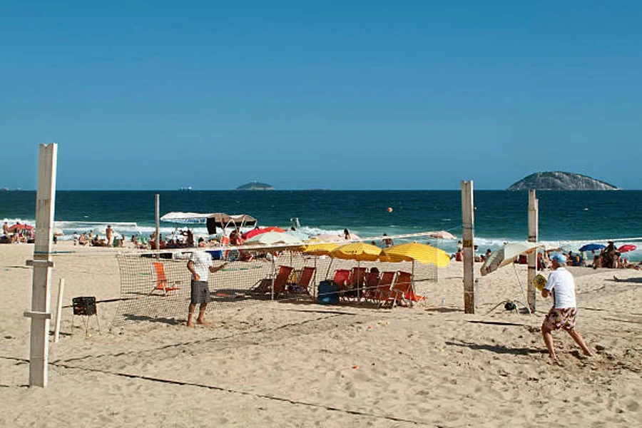 Two men playing beach tennis on a sunny day