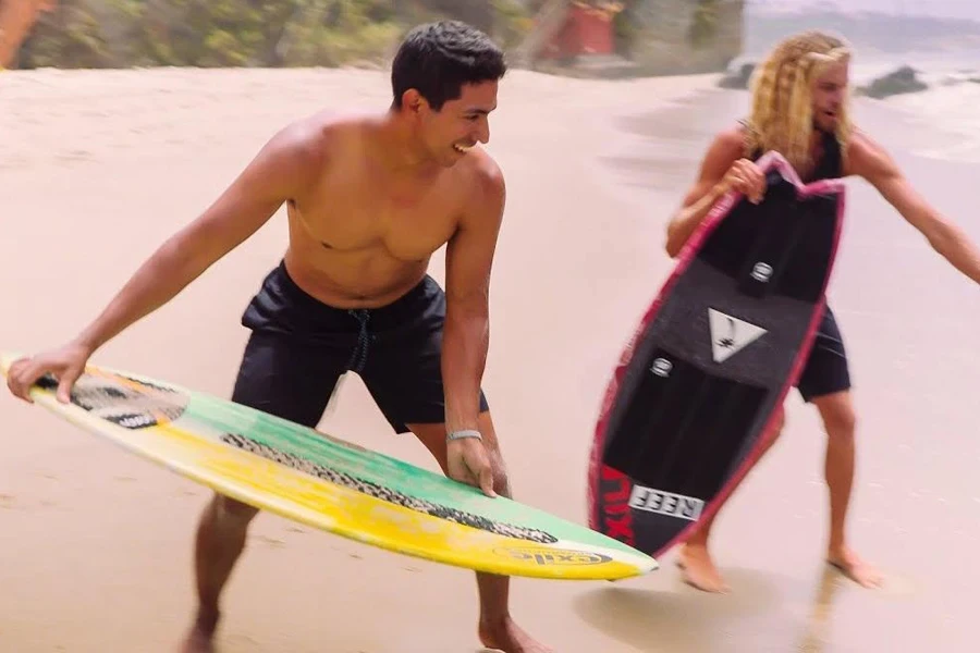 Two men playing with skimboards