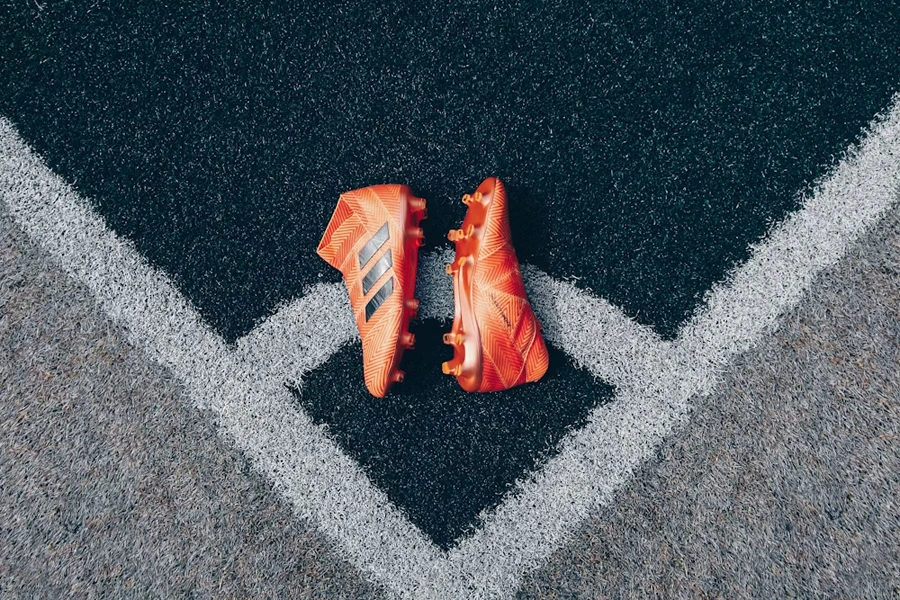 Two orange soccer shoes on a field
