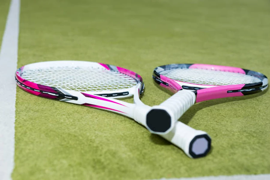 Two pink and white tennis racquets on grass court