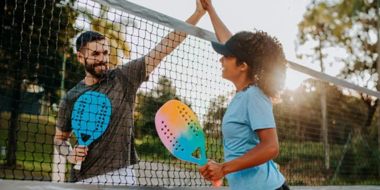 Two players high-fiving at beach tennis net
