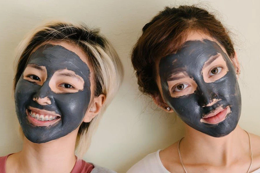 Duas mulheres sorridentes com máscaras faciais de carvão