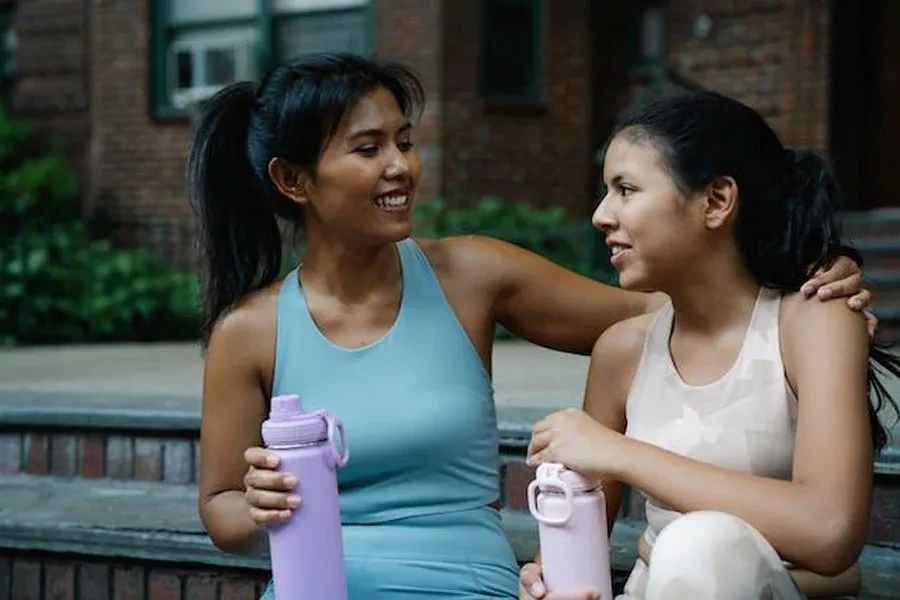 Dos mujeres sosteniendo sus botellas de agua.