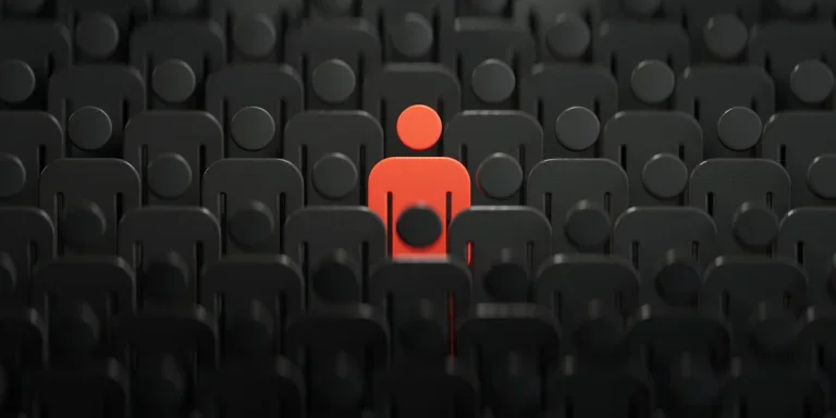 Unique red human figure standing out among darker ones