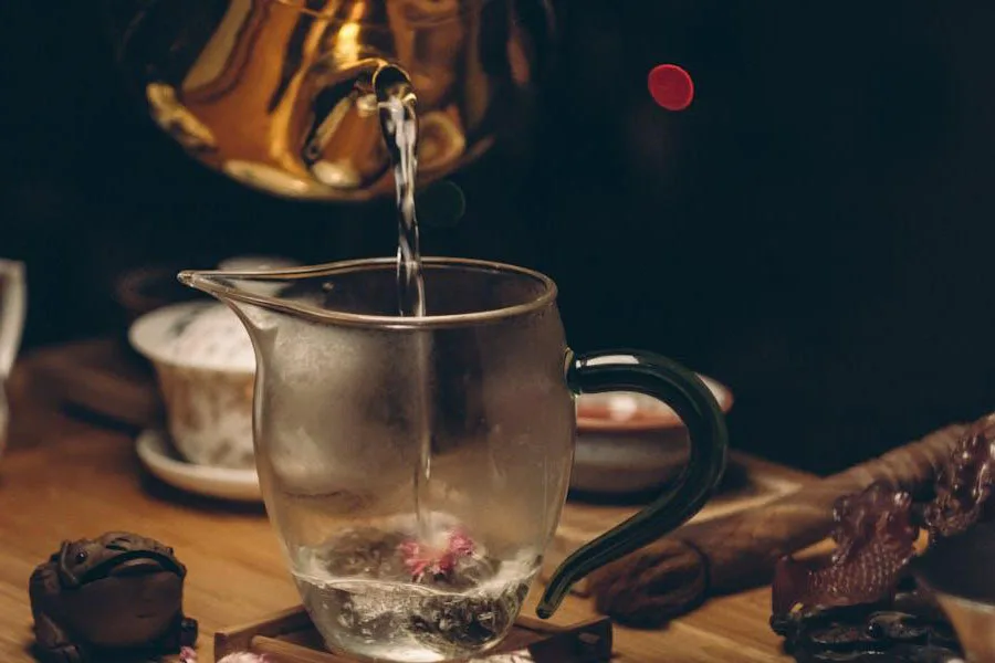 Water being poured from tea kettle into glass cup