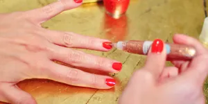 Frau trägt Nagelkleber auf ihre Nägel auf