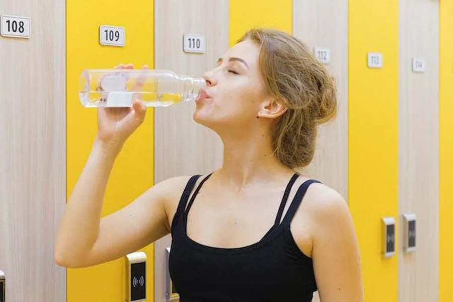 Mulher bebendo de uma garrafa de água reutilizável