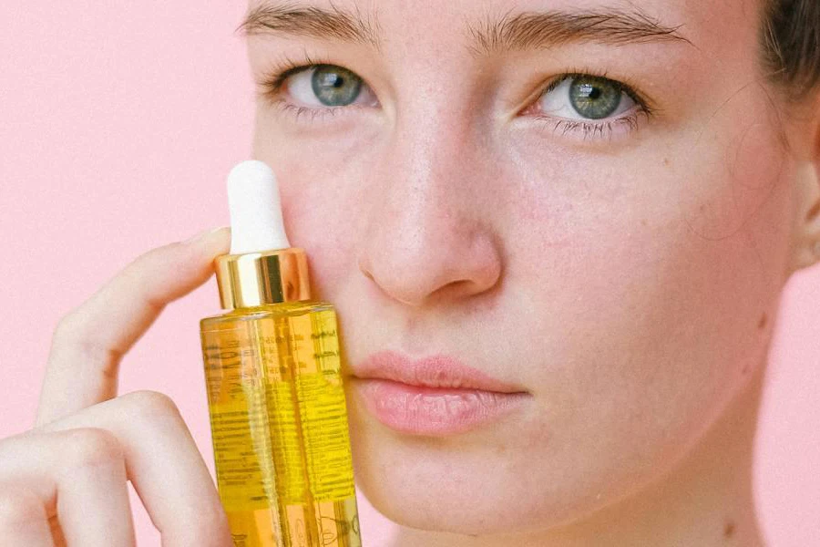 Mujer sosteniendo un aceite facial cerca de su cara