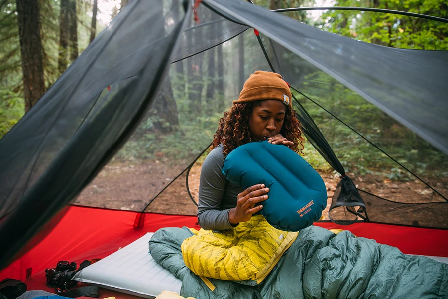 Mulher inflando uma almofada de acampamento azul