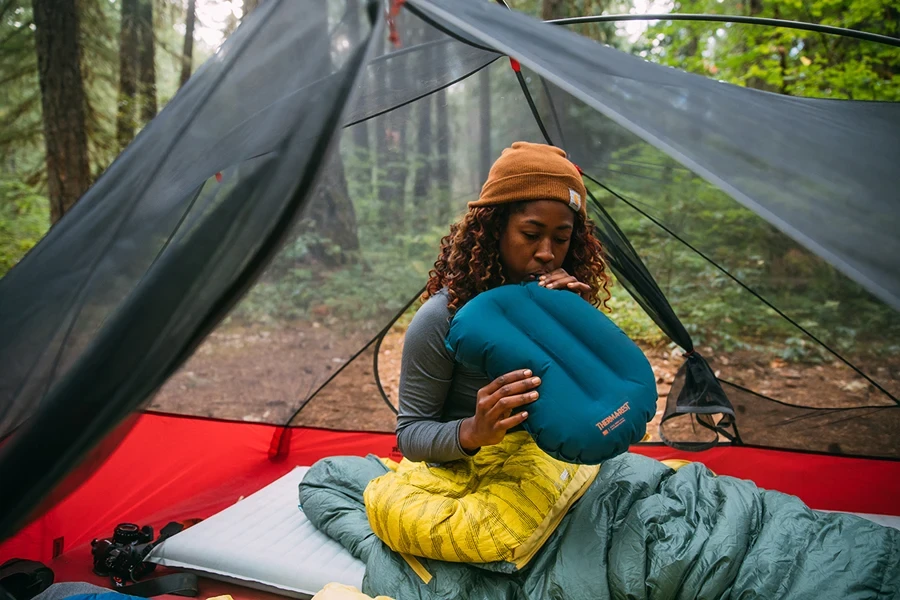 Frau bläst ein blaues Campingkissen auf