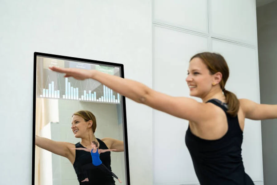 Wanita yang melakukan gerakan pilates di depan cermin pintar