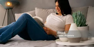 Mujer relajándose en un sofá, con un difusor de aromaterapia en primer plano