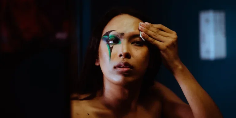 Woman removing makeup in front of a mirror