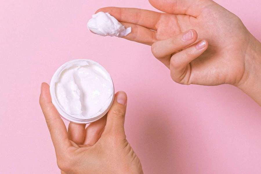 Woman scooping up cream facial cleansers