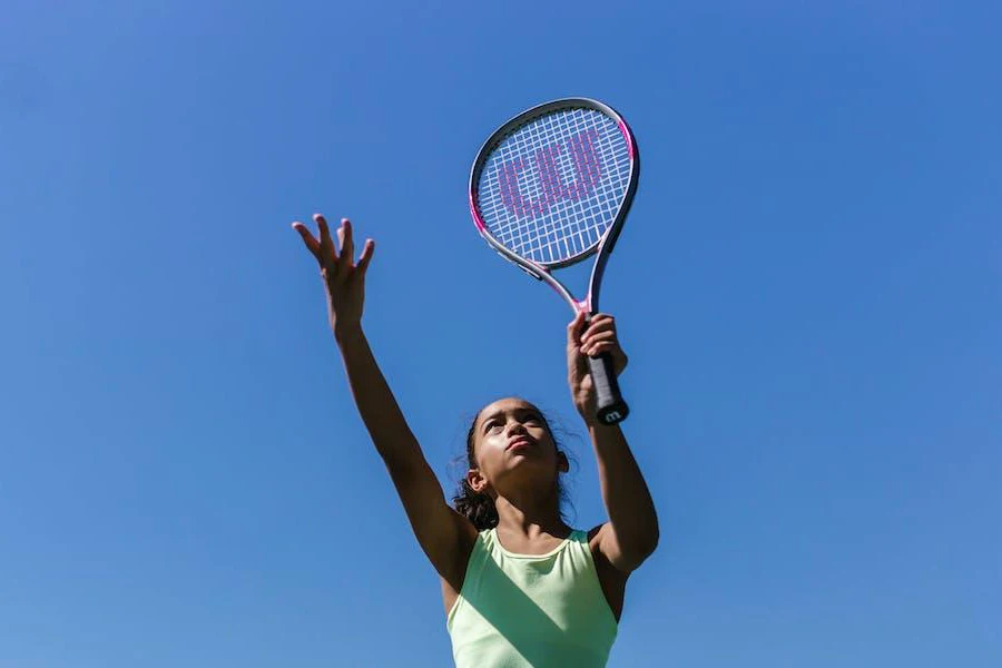 Wanita yang melayani dengan raket tenis