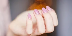 ピンクの手入れの行き届いた爪を披露する女性