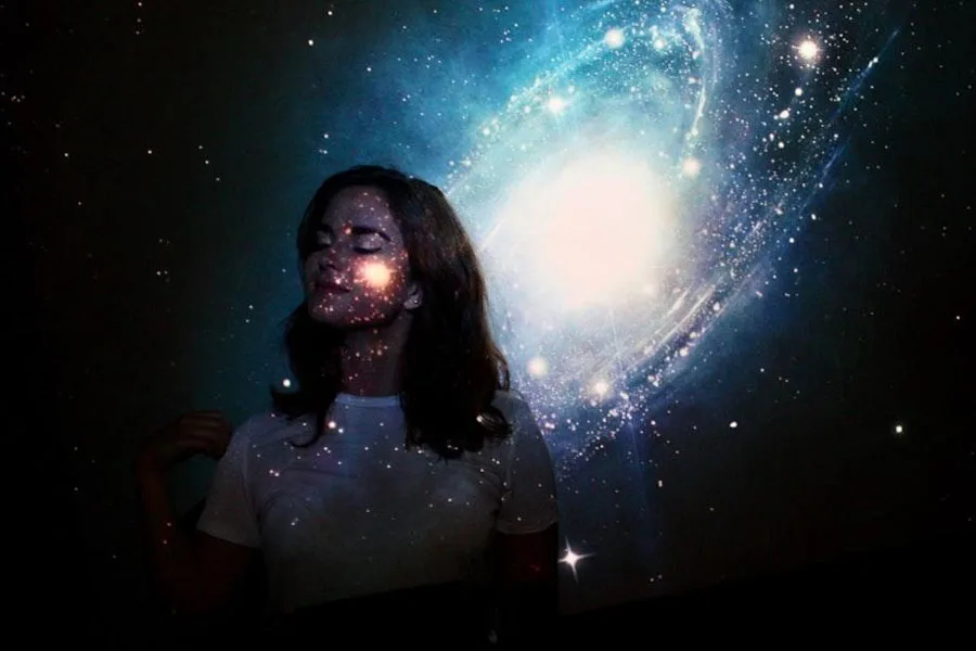 Woman standing against wall with galaxy light projection