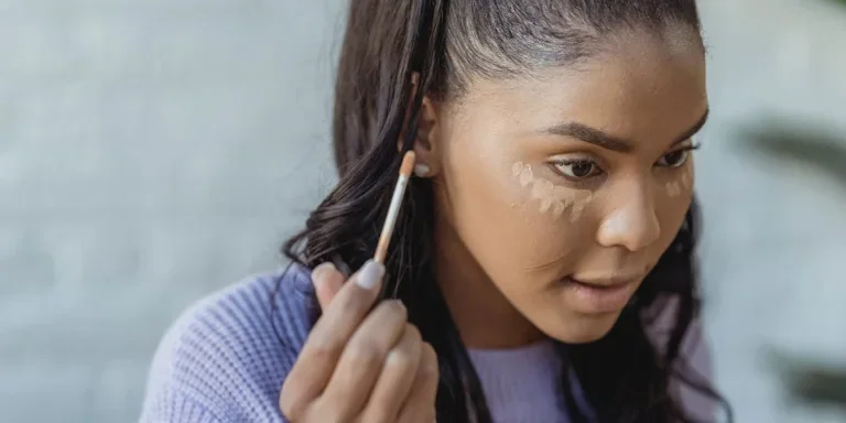 Woman using a concealer under her eyes