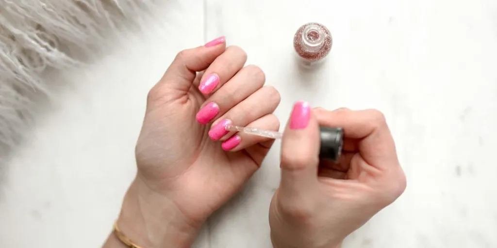 爪にピンクのポリッシュを使用している女性