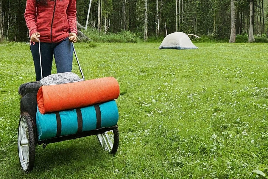 Frau benutzt einen Wagen, um Dinge zu ihrem Campingplatz zu transportieren
