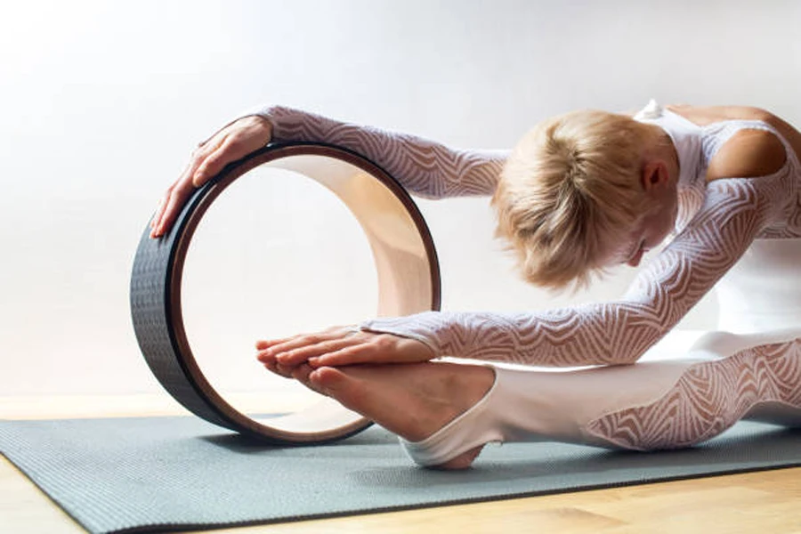 Frau nutzt Kork-Yoga-Rad, um ihr Bein zu strecken