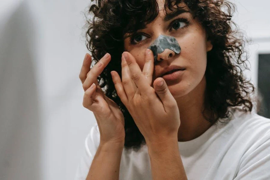 Femme utilisant des bandes de pores pour nettoyer les pores