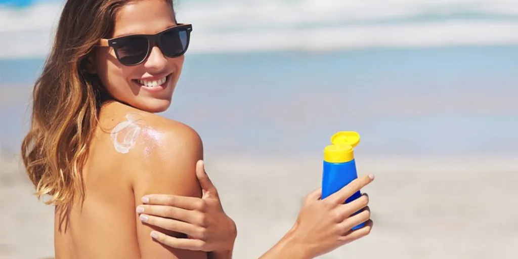 Mulher usando loção bronzeadora na praia
