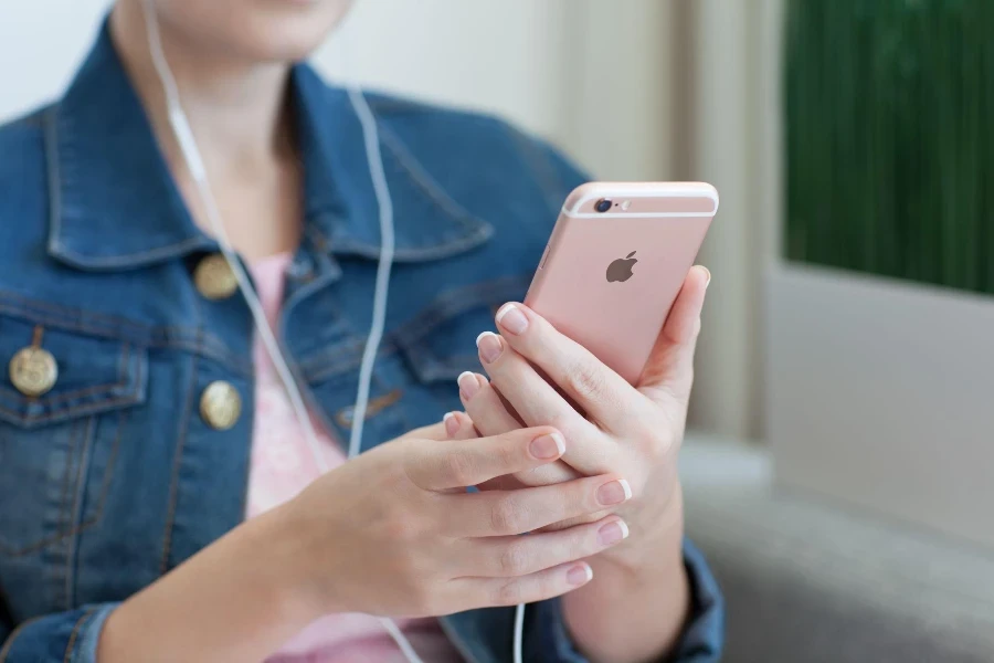 Woman with headphones holding in the hand iPhone