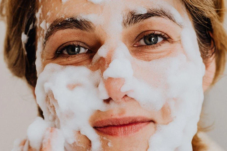 Mujer con espuma en la cara de limpiador facial