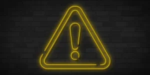 Yellow neon danger sign on brick wall