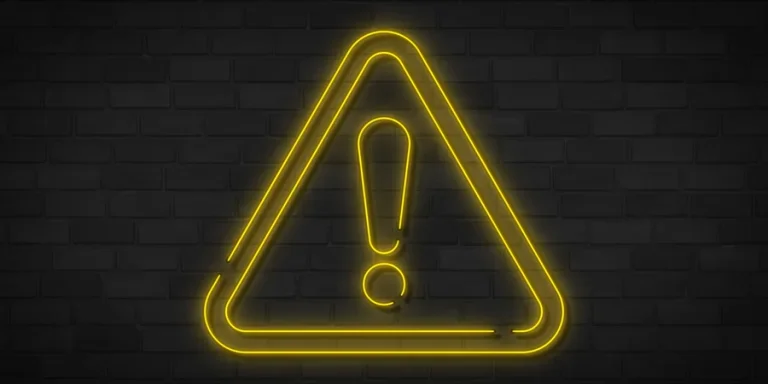 Yellow neon danger sign on brick wall